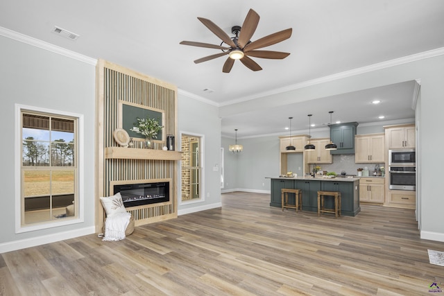 living area with light wood finished floors, baseboards, visible vents, ceiling fan with notable chandelier, and a fireplace
