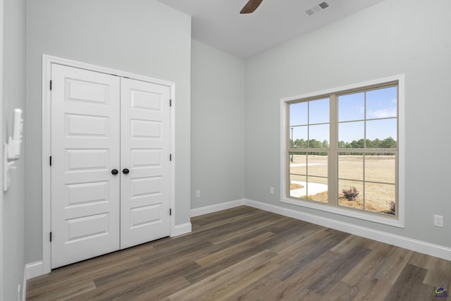 unfurnished bedroom with baseboards, dark wood-style flooring, visible vents, and a closet