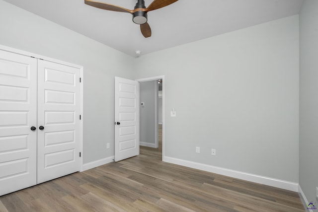 unfurnished bedroom featuring wood finished floors, ceiling fan, baseboards, and a closet