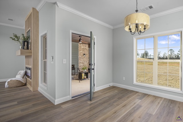 unfurnished dining area featuring crown molding, wood finished floors, baseboards, and visible vents