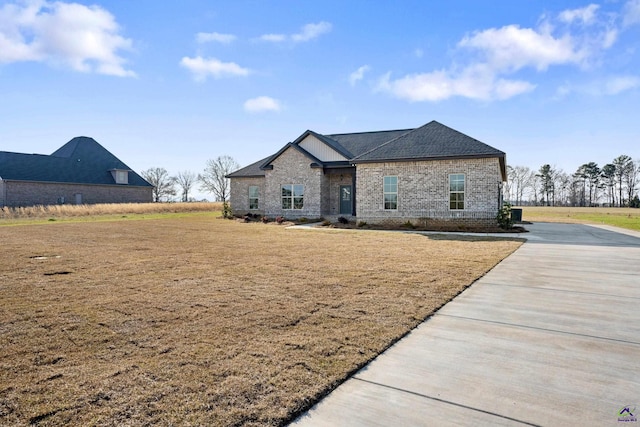 view of front facade featuring driveway, brick siding, and a front yard