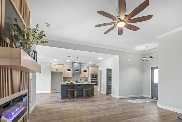 living area with ceiling fan with notable chandelier, light wood-style flooring, baseboards, ornamental molding, and recessed lighting