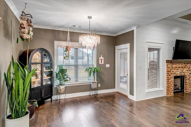 dining room with crown molding, wood finished floors, an inviting chandelier, baseboards, and visible vents