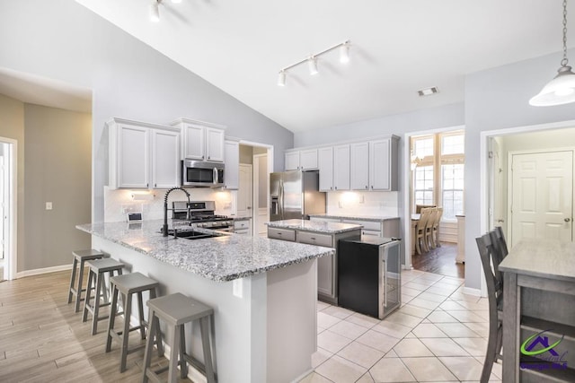 kitchen with a kitchen island, rail lighting, appliances with stainless steel finishes, and a sink