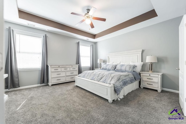 bedroom featuring a ceiling fan, a tray ceiling, carpet, baseboards, and visible vents