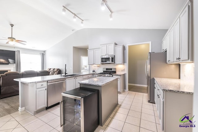 kitchen with lofted ceiling, stainless steel appliances, a sink, a peninsula, and open floor plan