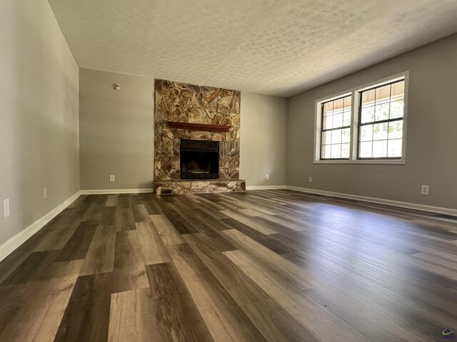 2045 Greentree Pkwy, Macon, GA 31220 - unfurnished living room with baseboards, a stone fireplace, a textured ceiling, and dark wood-style floors