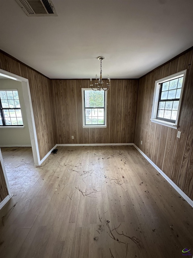 unfurnished dining area featuring baseboards, a notable chandelier, light wood finished floors, and visible vents