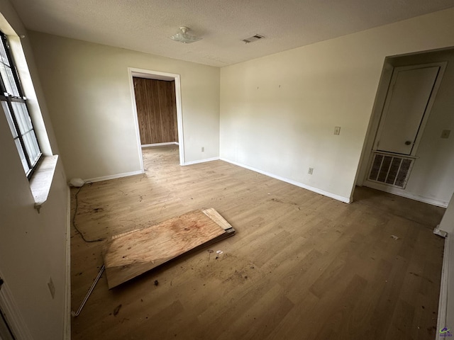 empty room featuring baseboards, wood finished floors, and visible vents