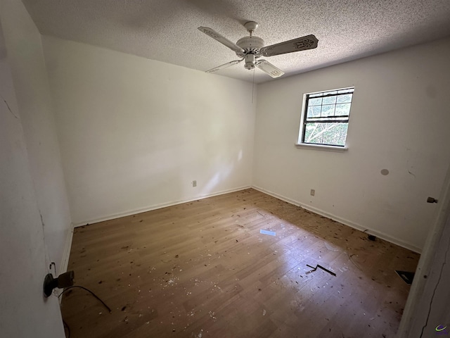 empty room featuring ceiling fan, baseboards, wood finished floors, and a textured ceiling