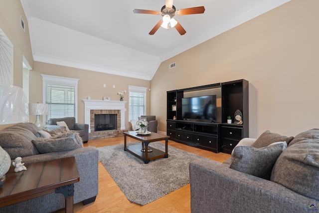 living room featuring light wood-style flooring, visible vents, lofted ceiling, a ceiling fan, and crown molding