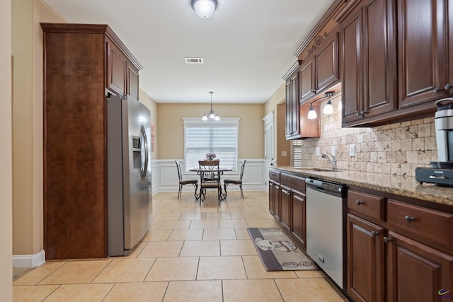 kitchen featuring stainless steel appliances, a sink, visible vents, backsplash, and a notable chandelier