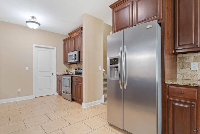 kitchen featuring light stone counters, decorative backsplash, light tile patterned flooring, baseboards, and appliances with stainless steel finishes