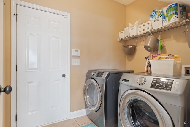 laundry room featuring separate washer and dryer, baseboards, laundry area, and light tile patterned flooring