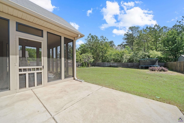 view of patio featuring a trampoline, a sunroom, and a fenced backyard