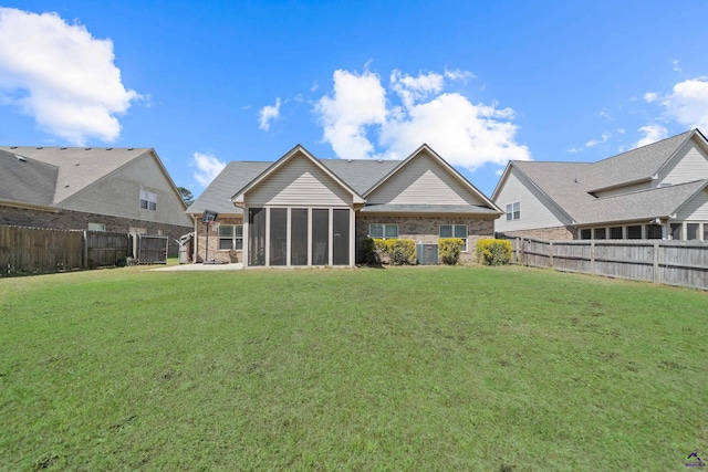 back of house with a lawn, a sunroom, a fenced backyard, and brick siding