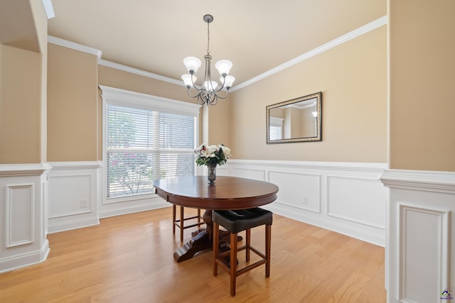 dining area featuring crown molding, an inviting chandelier, light wood finished floors, and a decorative wall