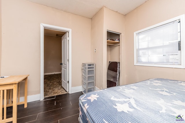 bedroom with wood finished floors, a closet, and baseboards