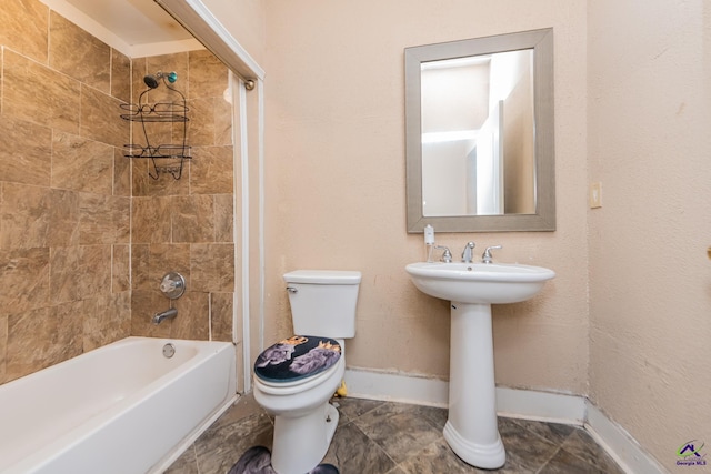 bathroom with washtub / shower combination, toilet, and baseboards