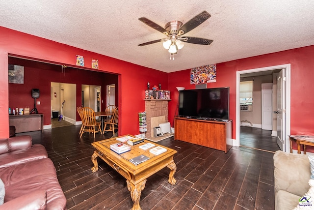 living area with baseboards, a ceiling fan, wood finished floors, and a textured ceiling