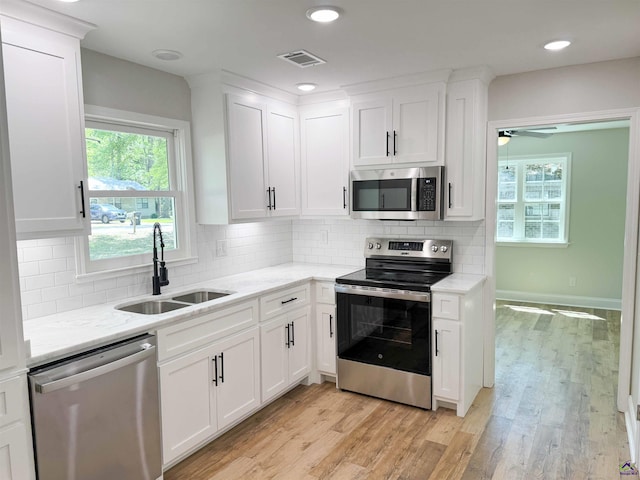 407 Frank Satterfield Rd, Perry, GA 31069 - kitchen featuring appliances with stainless steel finishes, a sink, white cabinetry, light wood-style floors, and light stone countertops