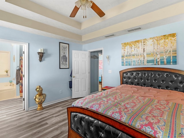 bedroom featuring wood finished floors, visible vents, connected bathroom, and baseboards