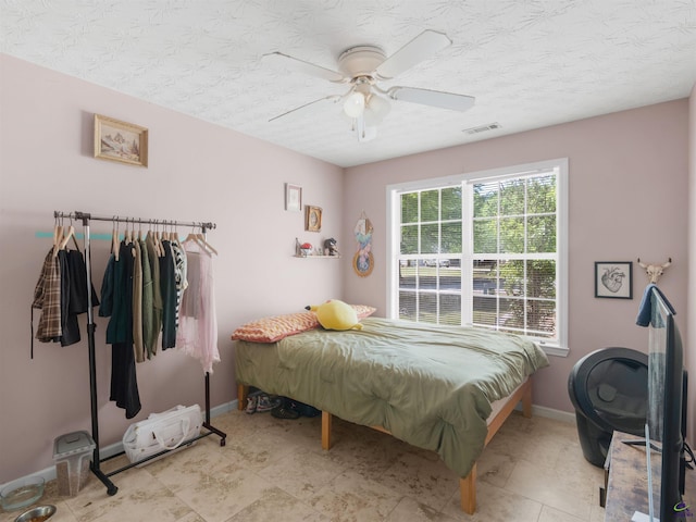 bedroom featuring a textured ceiling, visible vents, ceiling fan, and baseboards