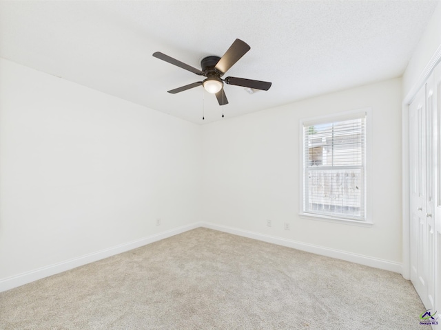 carpeted spare room with ceiling fan and baseboards