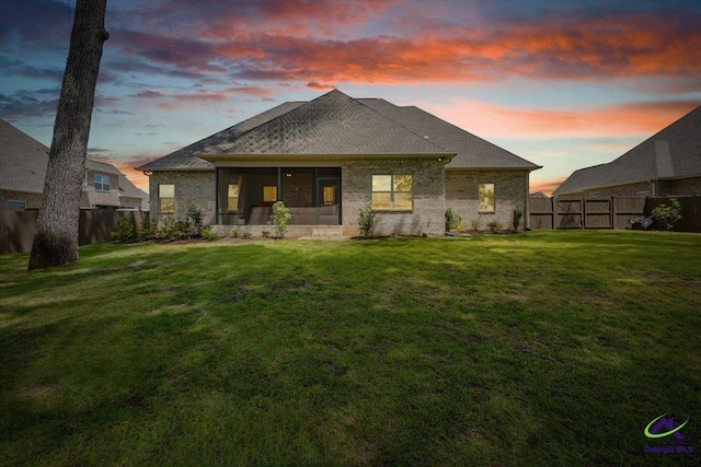 315 Apalachee Way, Bonaire, GA 31005 - back of property at dusk with a lawn, a sunroom, a fenced backyard, and brick siding