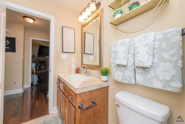 105 Taconic Ct, Bonaire, GA 31005 - bathroom featuring wood finished floors, toilet, a fireplace, vanity, and baseboards