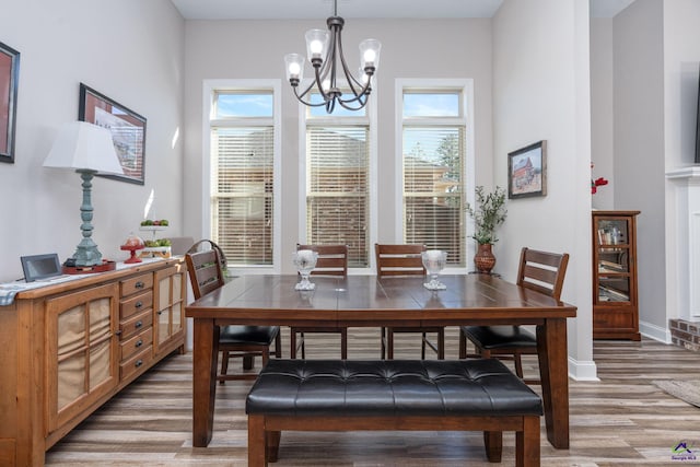 dining room with an inviting chandelier, baseboards, light wood-style flooring, and plenty of natural light