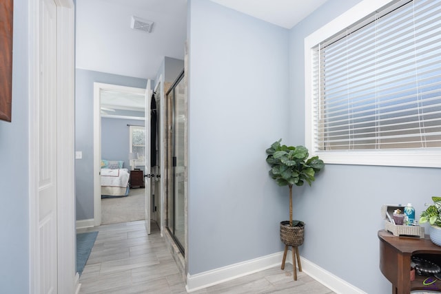 hall with baseboards, visible vents, and light wood-type flooring