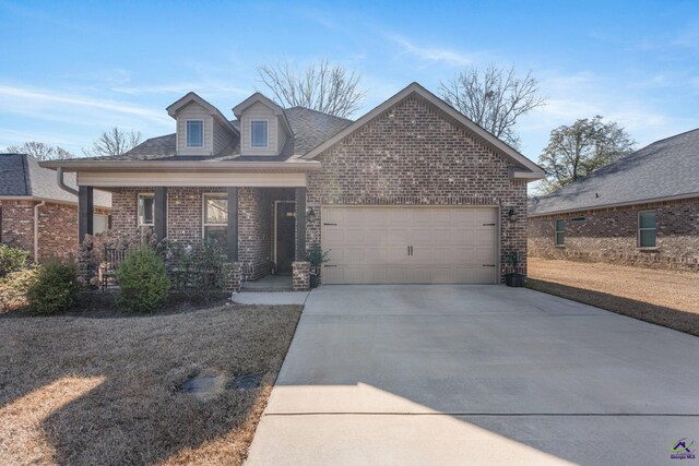 view of front of house with covered porch, concrete driveway, brick siding, and a garage