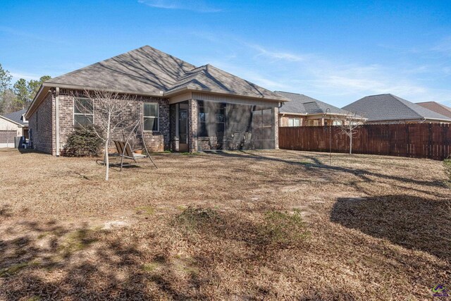 back of house with brick siding and fence