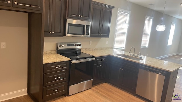 139 Rolling Woods Cir, Warner Robins, GA 31088 - kitchen with light stone counters, a sink, light wood finished floors, stainless steel appliances, and a peninsula