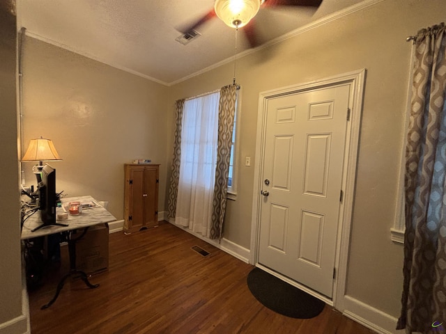 foyer entrance with dark wood-style flooring, a ceiling fan, visible vents, and ornamental molding