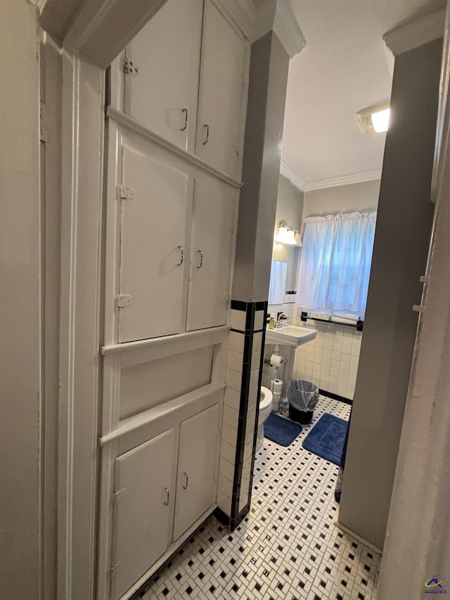 bathroom with crown molding, tile walls, a sink, and tile patterned flooring