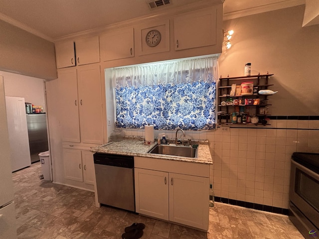 kitchen with appliances with stainless steel finishes, tile walls, a sink, ornamental molding, and white cabinetry
