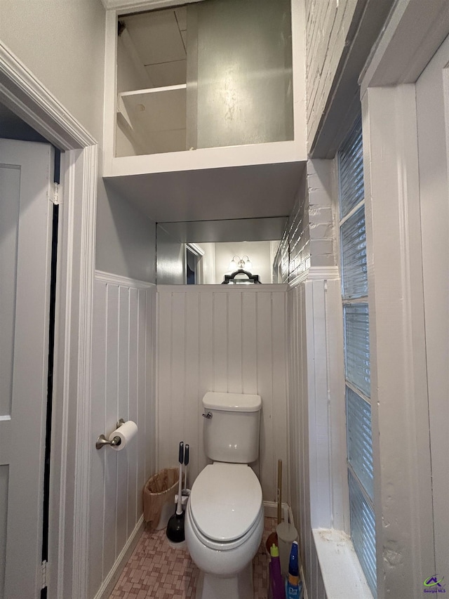 bathroom with a wainscoted wall and toilet