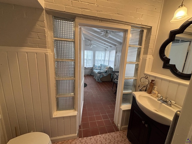 half bath featuring ceiling fan, wainscoting, lofted ceiling, and vanity