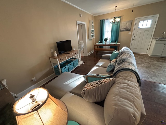 living room with crown molding, baseboards, a healthy amount of sunlight, and an inviting chandelier