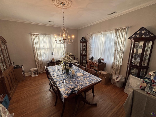 dining space with a healthy amount of sunlight, wood-type flooring, a notable chandelier, and visible vents