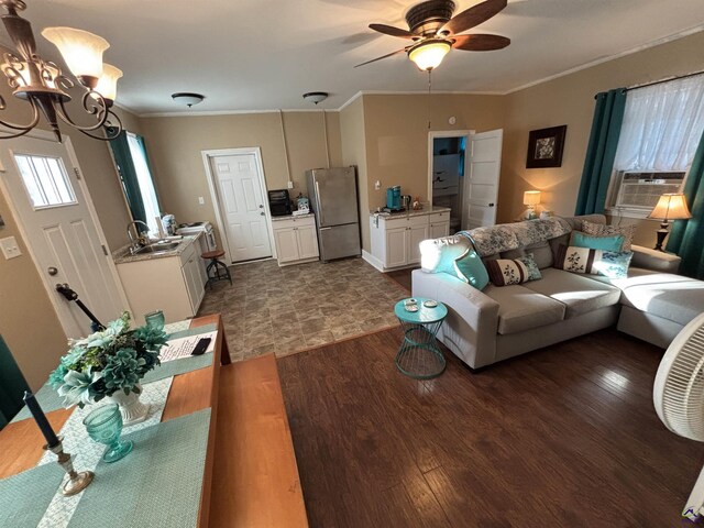living area featuring crown molding, dark wood-type flooring, ceiling fan with notable chandelier, and cooling unit