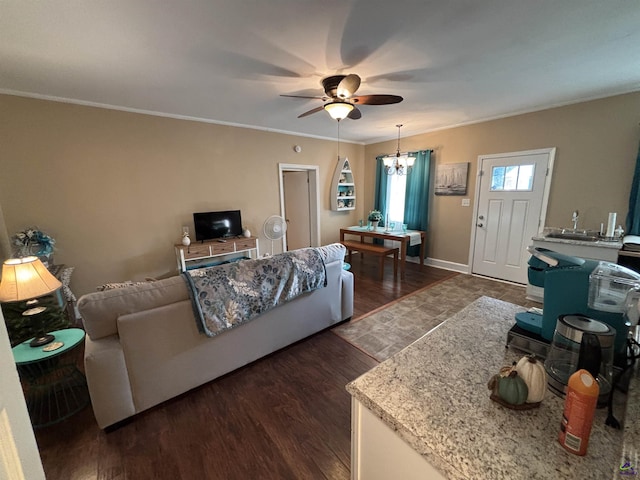 living room featuring crown molding, baseboards, ceiling fan with notable chandelier, and wood finished floors