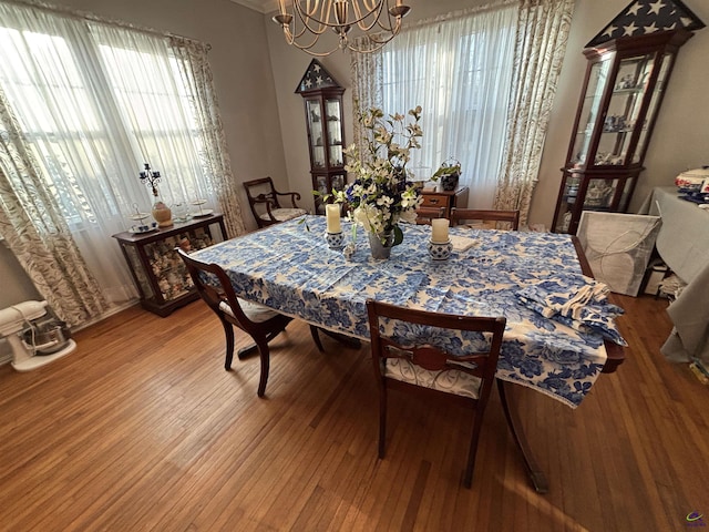 dining space featuring a chandelier, ornamental molding, and wood finished floors