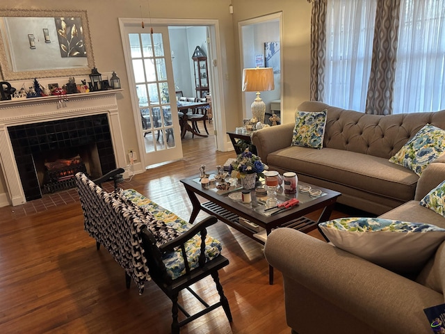 living room featuring a tiled fireplace, baseboards, and wood finished floors
