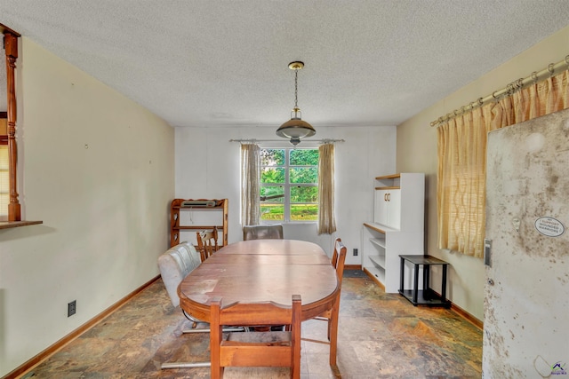 dining space featuring baseboards, stone finish flooring, and a textured ceiling