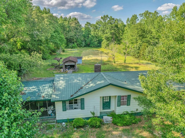 rear view of property with a gazebo, a chimney, a yard, and metal roof