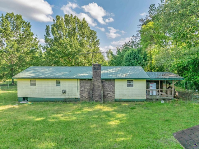 rear view of house with a wooden deck, a chimney, crawl space, metal roof, and a yard