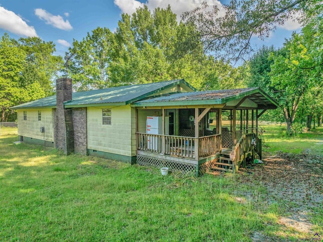 rear view of house with a yard, crawl space, a chimney, and metal roof